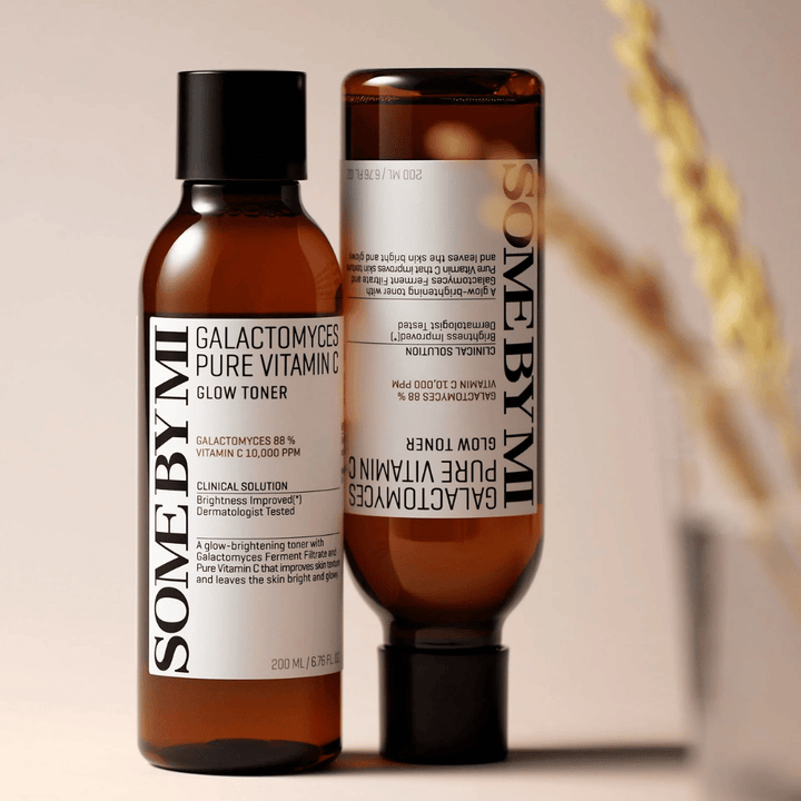 Obrázok SOME BY MI Galactomyces Pure Vitamin C Glow Toner. Fľaše majú elegantný dizajn s hnedými tónmi a čiernym uzáverom. Produkt obsahuje 88% galactomyces a 10 000 ppm vitamínu C, čo sľubuje zlepšiť žiarivosť pleti a poskytnúť sviežejší tón pleti.