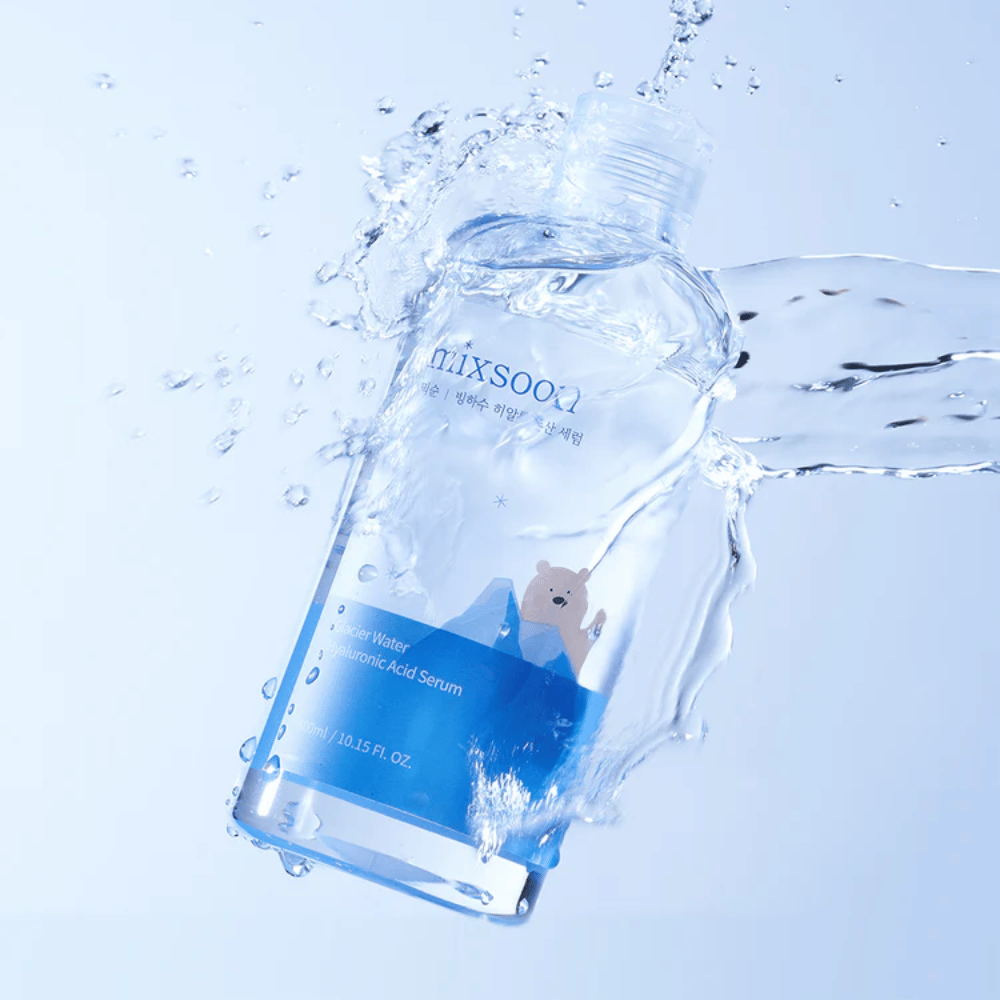 Fľaša Mixsoon Glacier Water Hyaluronic Acid Serum s modrou etiketou a motívom ľadového medveďa obklopená striekajúcou vodou na svetlomodrom pozadí.