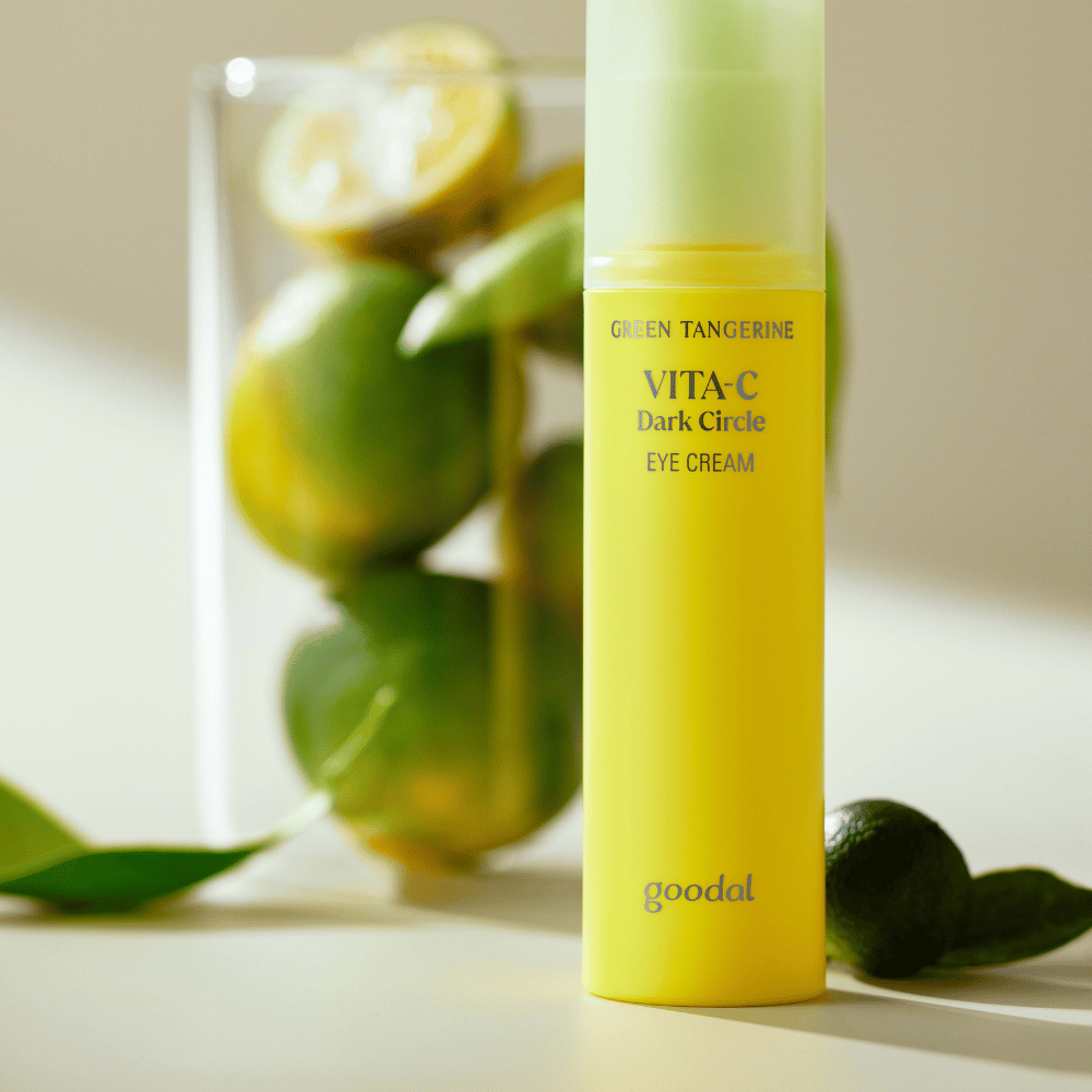 Fľaša Goodal Green Tangerine Vita C Dark Circle Eye Cream 30ml na stole vedľa limetky.