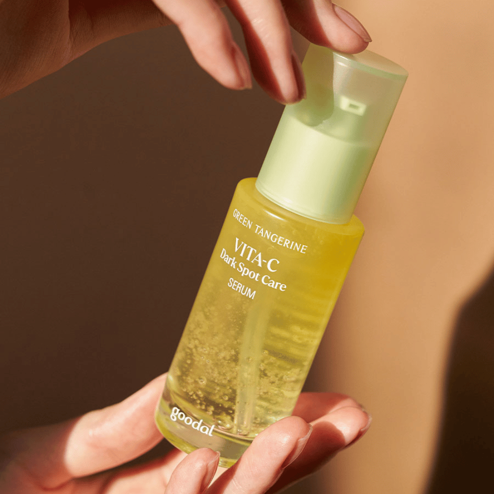 Osoba, ktorá drží fľašu Green Tangerine Vita C Dark Spot Care Serum 40ml od Goodal pre hyperpigmentáciu a starostlivosť o tmavé škvrny.