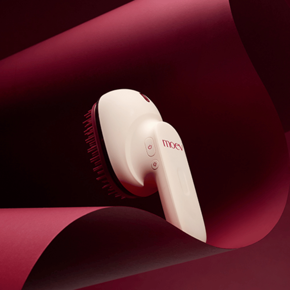 MOEV Hair Steamer Pro v elegantnom dizajne na červenom pozadí. Inovatívna kefa na starostlivosť o vlasy, ktorá používa paru a teplo na dodanie lesku, jemnosti a posilnenie zdravia vlasov.