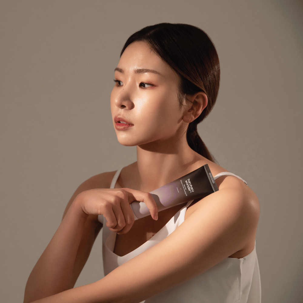 Mladá ázijská žena držiaca kefu v ruke, zatiaľ čo používa Haruharu Wonders Black Rice Moisture 5.5 Soft Cleansing Gel 100ml.