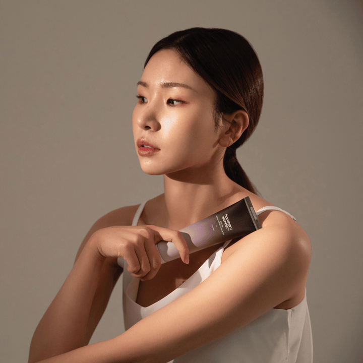 Mladá ázijská žena držiaca kefu v ruke, zatiaľ čo používa Haruharu Wonders Black Rice Moisture 5.5 Soft Cleansing Gel 100ml.