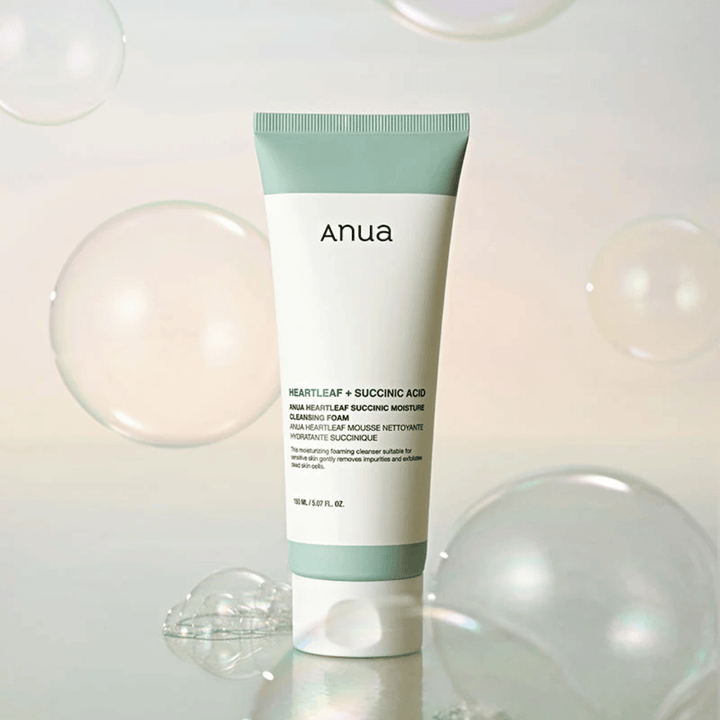 Produktová fotografia Anua Heartleaf + Succinic Acid Moisture Cleansing Foam obklopeného priehľadnými bublinkami. Obrázok posilňuje pocit jemného čistenia, sviežosti a nadýchanej peny.