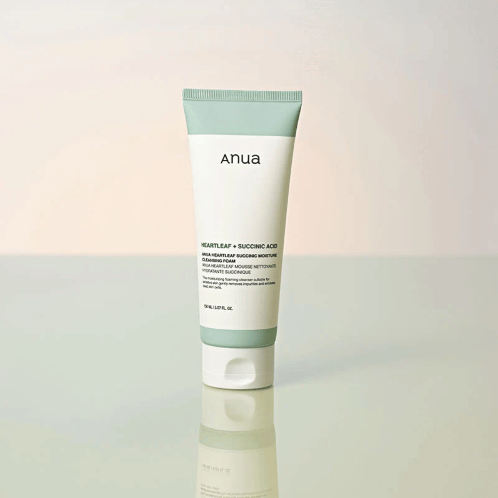 Samostatná produktová fotografia Anua Heartleaf + Succinic Acid Moisture Cleansing Foam. Produkt je zobrazený postojačky na reflexnom povrchu, ktorý jasne zvýrazňuje dizajn balenia a čistú estetiku značky.