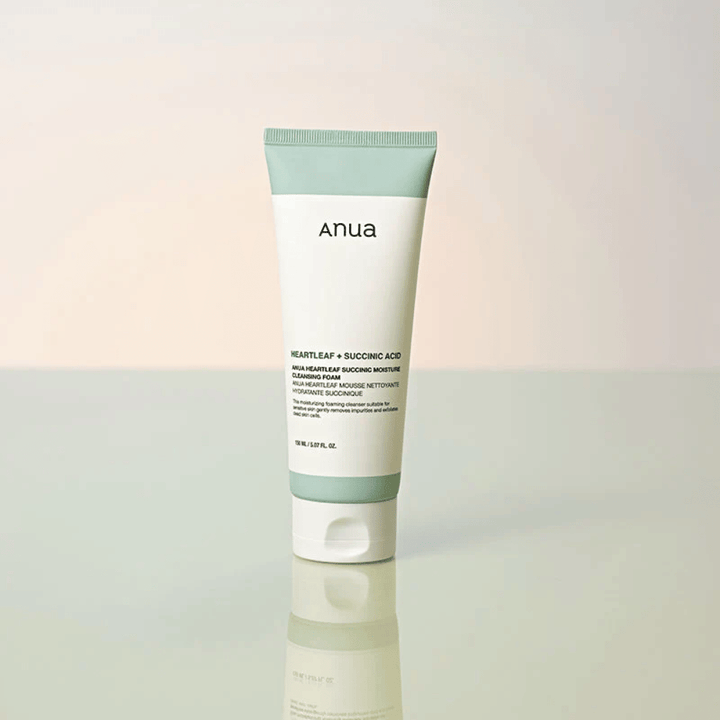 Samostatná produktová fotografia Anua Heartleaf + Succinic Acid Moisture Cleansing Foam. Produkt je zobrazený postojačky na reflexnom povrchu, ktorý jasne zvýrazňuje dizajn balenia a čistú estetiku značky.