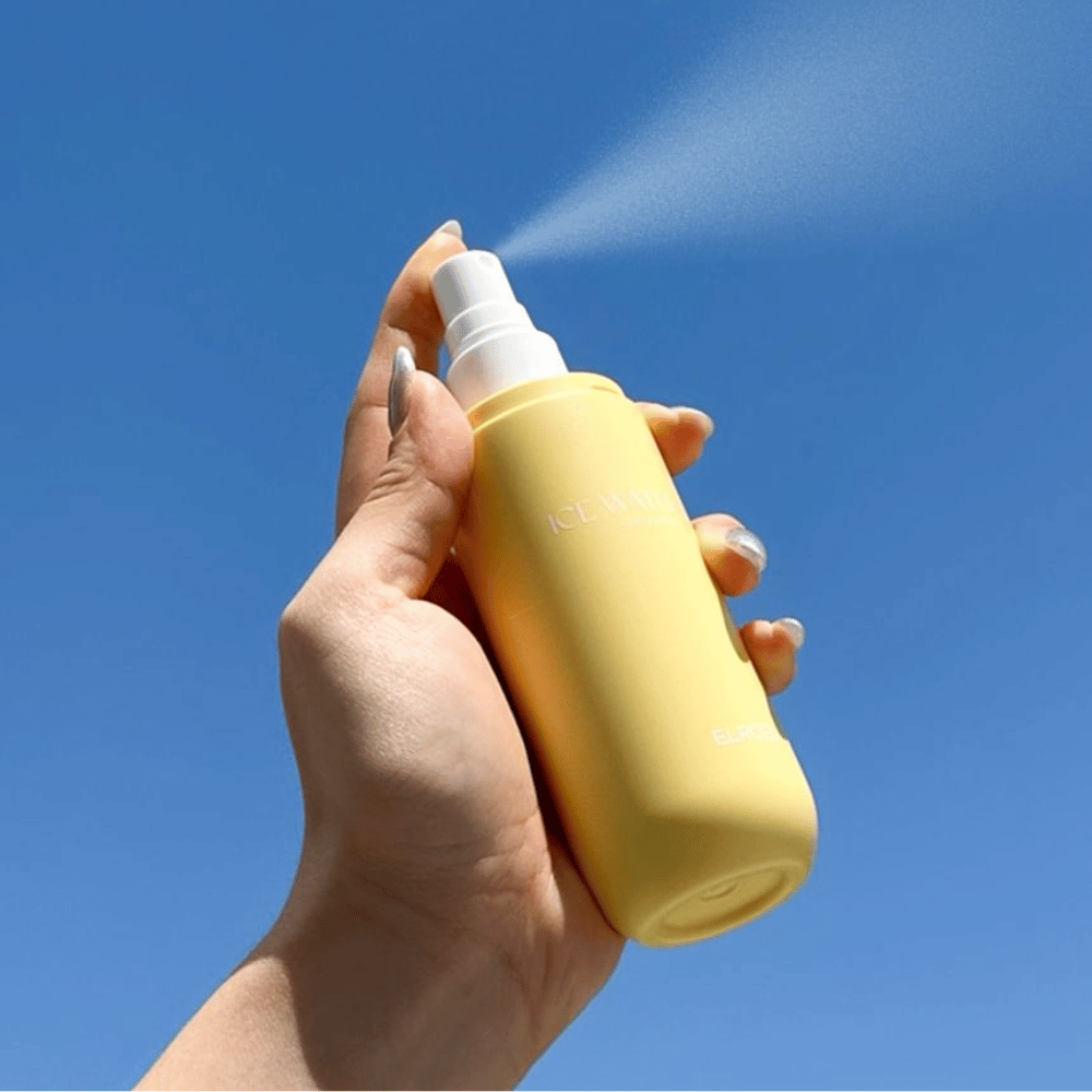 ELROEL Ice Water Sun Mist SPF 40 PA+++ slnečná hmla sa rozprašuje z fľaše proti modrej oblohe, ľahká slnečná ochrana, ktorá hydratuje a osviežuje pokožku