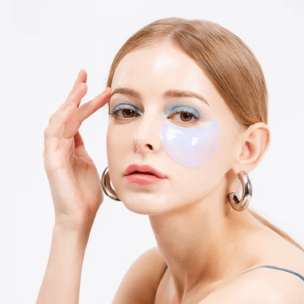 Model nosí modro-trblietavý hydrogelový očný vankúšik pod okom pre osviežujúci efekt.