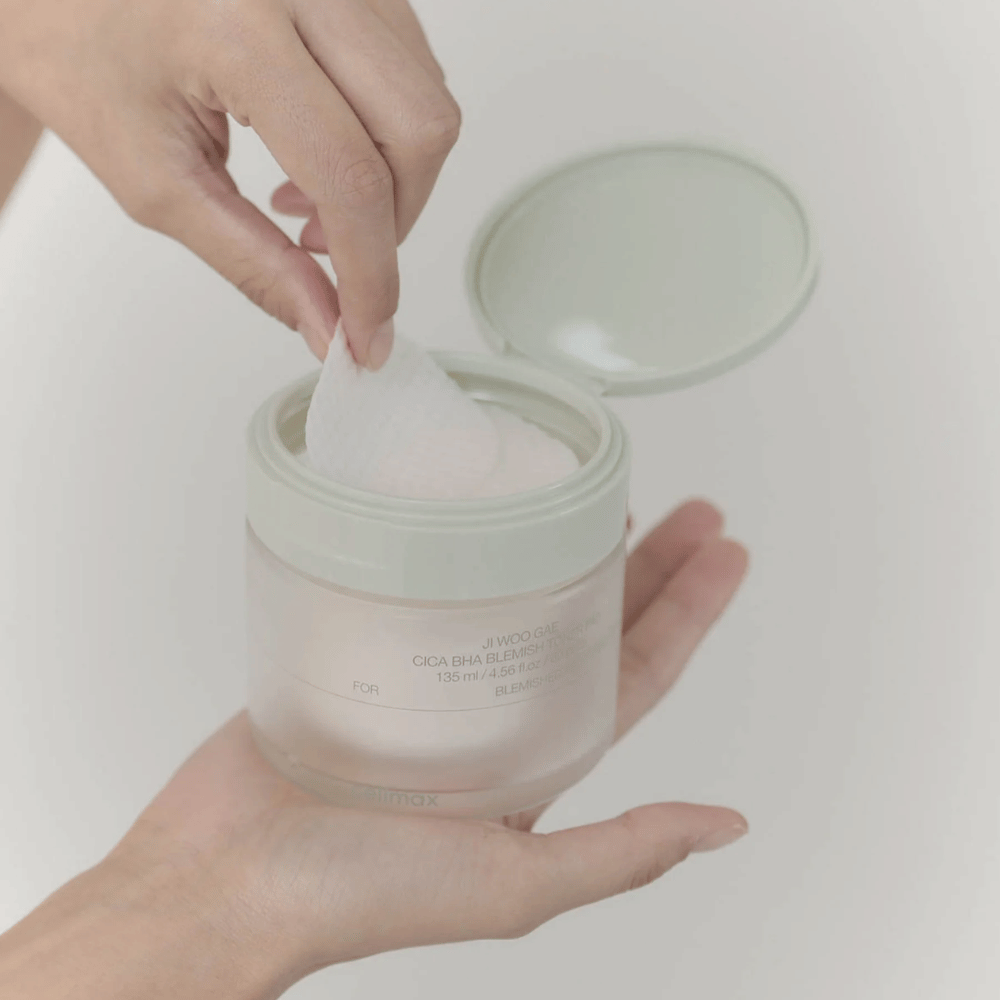 Ruka vyberá tonerovú podložku z nádoby Celimax Ji Woo Gae Cica BHA Blemish Toner Pad, ideálna pre nečistú pleť.