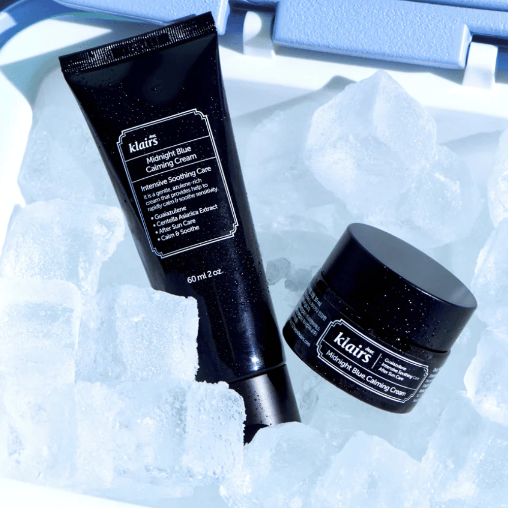 Tuba a nádoba Klairs Midnight Blue Calming Cream ležia na kockách ľadu, so zameraním na upokojujúce a hydratačné vlastnosti, na modrom pozadí.