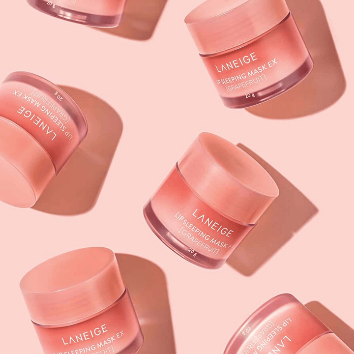 Štyri nádoby LANEIGE Lip Sleeping Mask Grapefruit 20g na ružovom pozadí, podporuje grapefruit a hydratáciu.