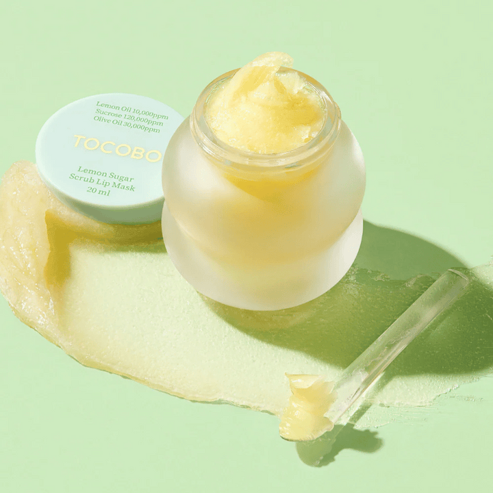 Otvorená nádoba s Tocobo Lemon Sugar Scrub Lip Mask na zelenom pozadí, s jasne viditeľným obsahom.