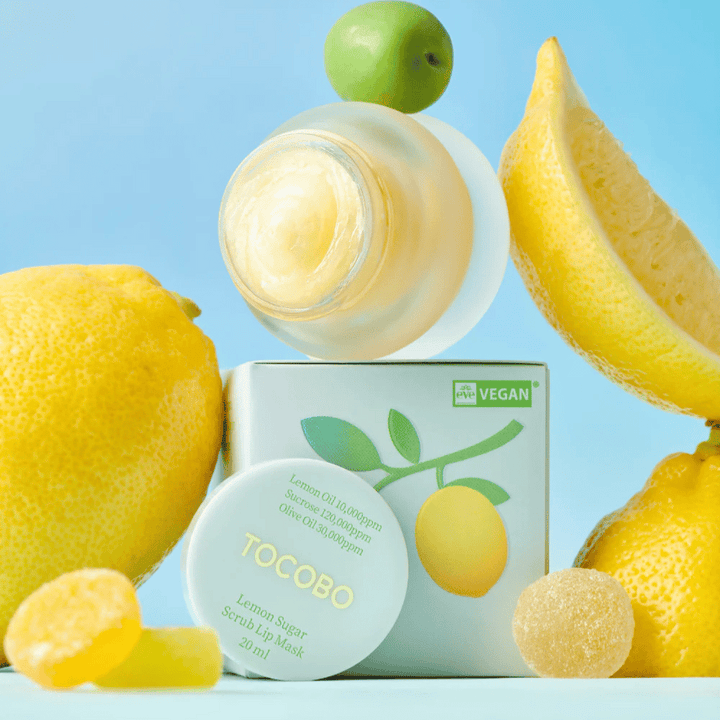 Nádoba s Tocobo Lemon Sugar Scrub Lip Mask umiestnená medzi citrónmi a obalom, označená ako vegánsky priateľská.