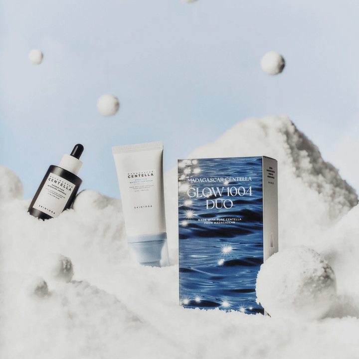 Obrázok zobrazuje sadu starostlivosti o pleť "Madagascar Centella Glow 1004 Duo" od SKIN1004, umiestnenú na pozadí, ktoré zobrazuje sneh a oblohu.