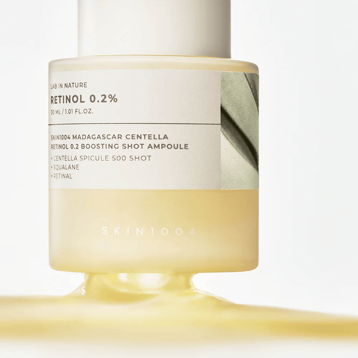Detailný záber na SKIN1004 Madagascar Centella Retinol 0.2 Boosting Shot Ampoule ukazujúci svetložltú, hodvábnu konzistenciu retinolového séra pre nočnú obnovu pokožky.