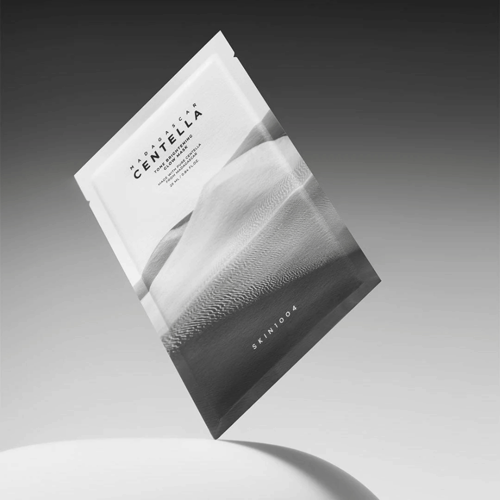 Balenie Sheet mask od SKIN1004 vznášajúce sa na sivom pozadí s minimalistickým dizajnom.