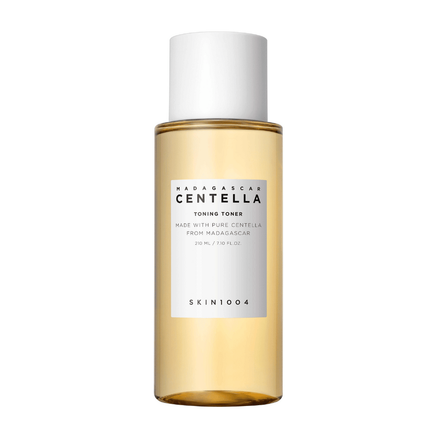 Obrázok zobrazuje fľašu s pleťovým tonerom, označenú ako "Madagascar Centella Toning Toner" od SKIN1004. Produkt je uvedený ako obsahujúci 210 ml alebo 7,10 fl.oz a je vyrobený s čistou Centellou z Madagaskaru. Balenie je jednoduché a elegantné s priehľadnou fľašou a zlatistou tekutinou vo vnútri, čo vytvára pocit luxusu a čistoty. Logo značky SKIN1004 je jasne viditeľné v dolnej časti etikety.