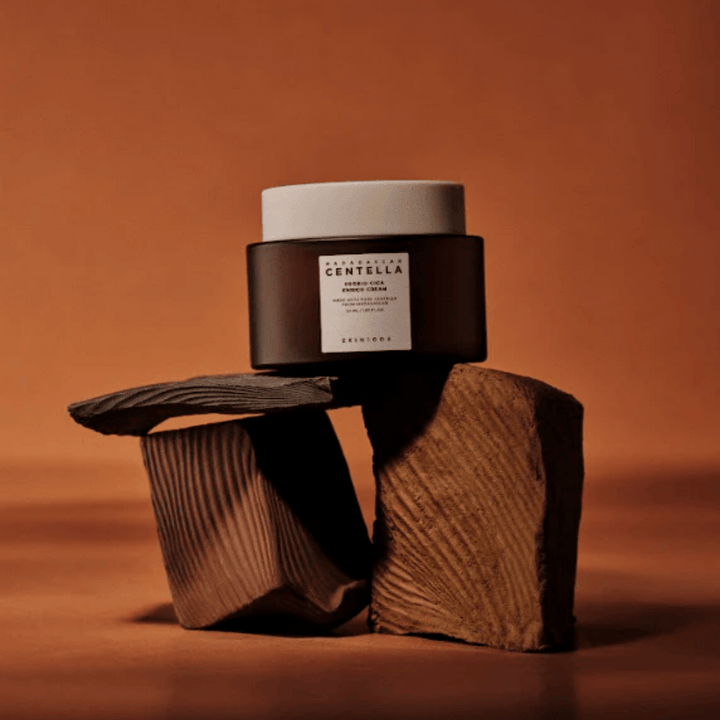 SKIN1004 Madagascar Centella Probio-Cica Enrich Cream v elegantnej hnedej sklenenej nádobe na dekoratívnych drevených blokoch – výživný kórejský pleťový krém, ktorý posilňuje kožnú bariéru.
