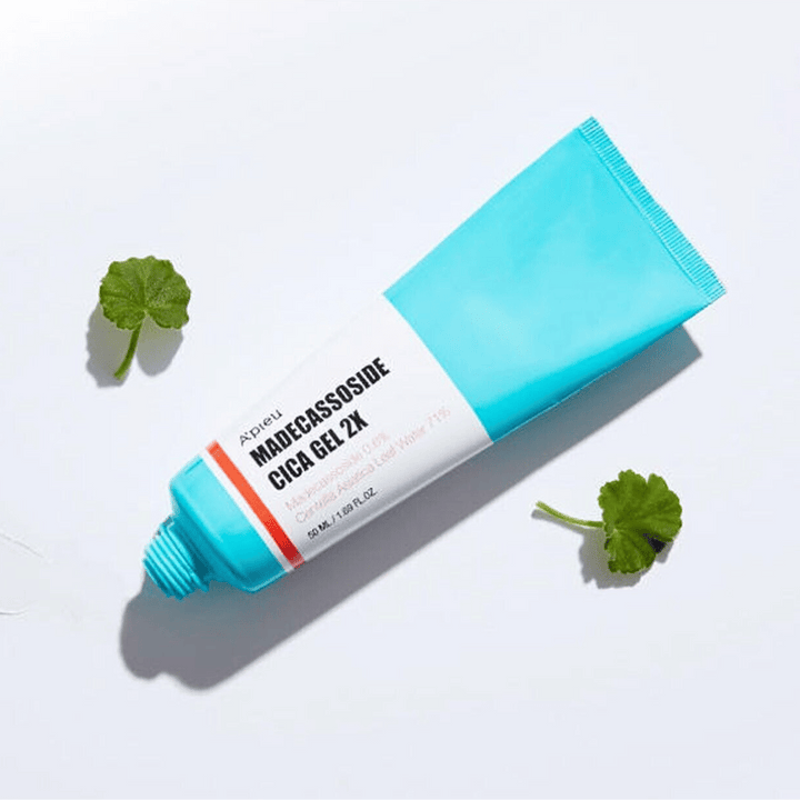 A’pieu Madecassoside Cica Gel 2X v modrej tube s bielou etiketou, obklopenou tromi zelenými listami centella asiatica na bielom pozadí.