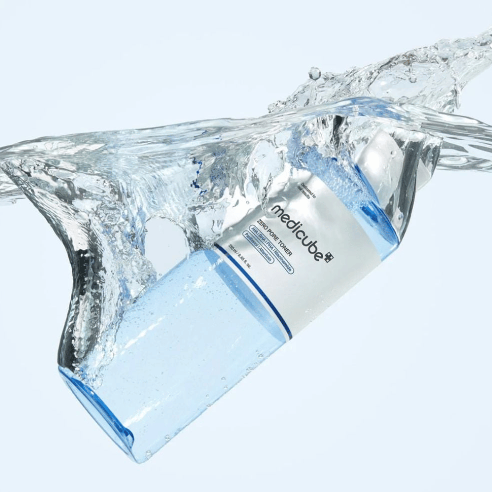 Medicube Zero Pore Toner 250 ml, exfoliačné tonikum s AHA, BHA a PHA. Priehľadná modrá fľaša obklopená veľkým šplechnutím vody.