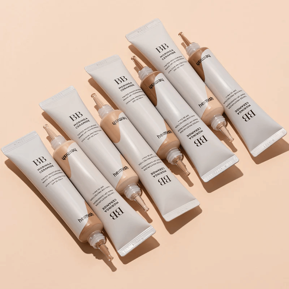 Viacero túb Heimish Moringa Ceramide BB Cream usporiadaných na svetlobéžovom pozadí. Obrázok zvýrazňuje rôzne odtiene a elegantný, minimalistický dizajn balenia produktu.