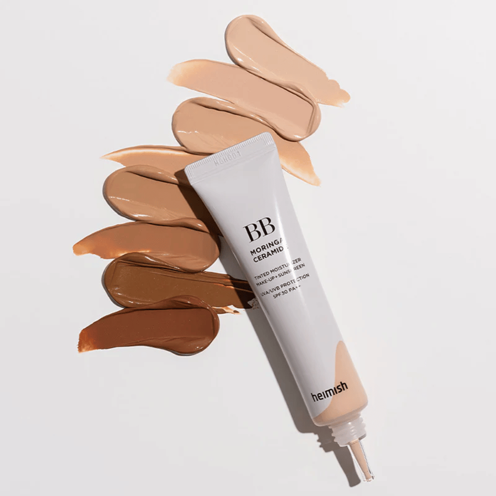 Heimish Moringa Ceramide BB Cream obklopený viacerými vzorkami odtieňov v rôznych tónoch pleti. Obrázok ukazuje širokú škálu farieb produktu a krémovú konzistenciu, ktorá poskytuje prirodzené krytie a jednotný tón pleti.