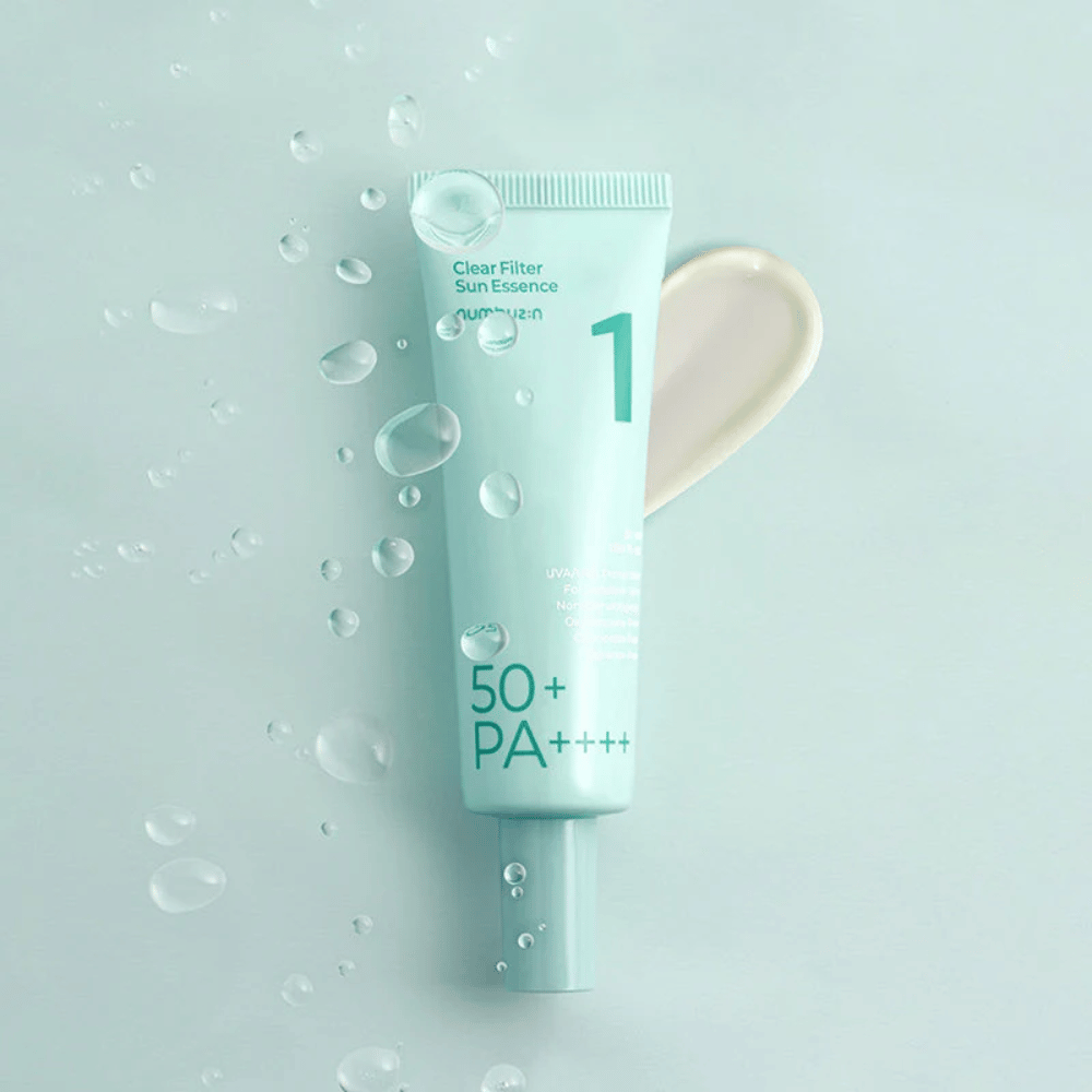 Svetlomodrá tuba s No.1 Clear Filter Sun Essence SPF 50+ PA++++. Tuba je ozdobená kvapkami vody a vedľa je zobrazená kvapka produktu. Produkt je navrhnutý na poskytovanie vysokej ochrany proti slnečnému žiareniu a ochranu proti UVA/UVB lúčom.