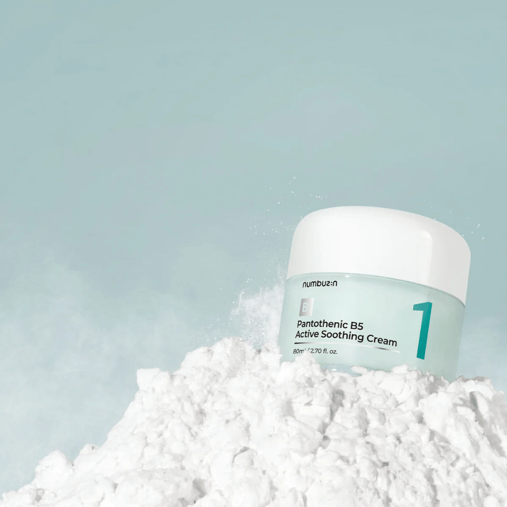 Numbuzin No.1 Pantothenic B5 Active Soothing Cream 80 ml v svetlozelenej nádobe s bielym vrchnákom, umiestnená na kope bieleho prášku na svetlom pozadí.