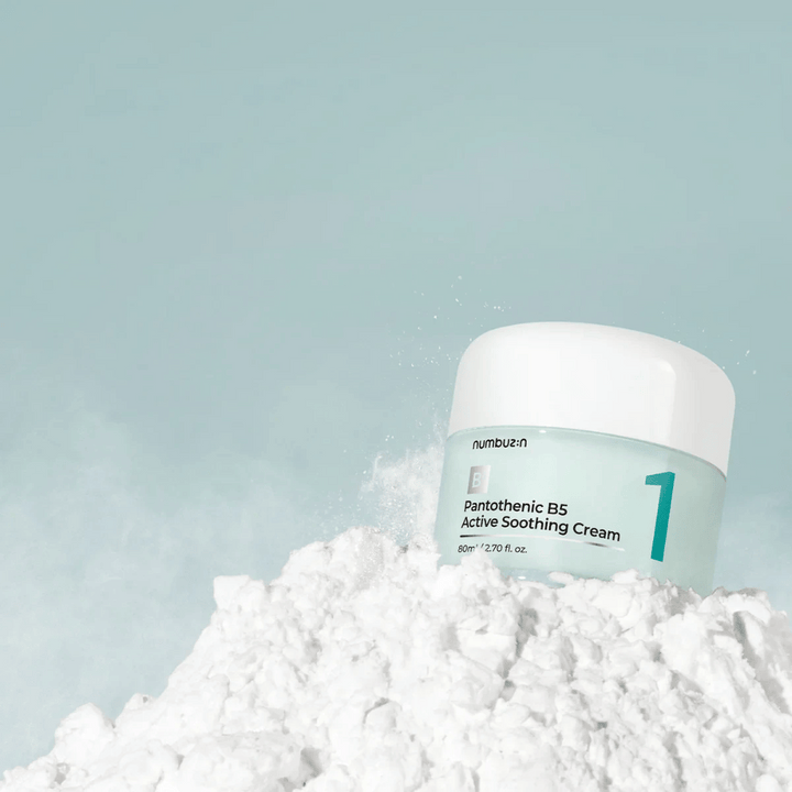 Numbuzin No.1 Pantothenic B5 Active Soothing Cream 80 ml v svetlozelenej nádobe s bielym vrchnákom, umiestnená na kope bieleho prášku na svetlom pozadí.