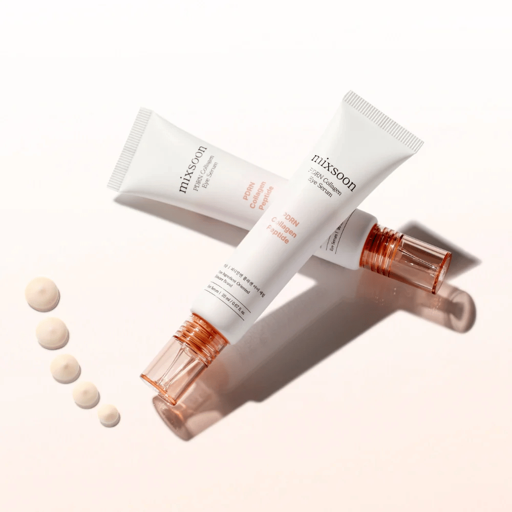 Dve tuby Mixsoon PDRN Collagen Eye Serum sú prekrížené s malými kvapkami séra. Ľahká očná starostlivosť, ktorá hydratuje a vyhladzuje vrásky.