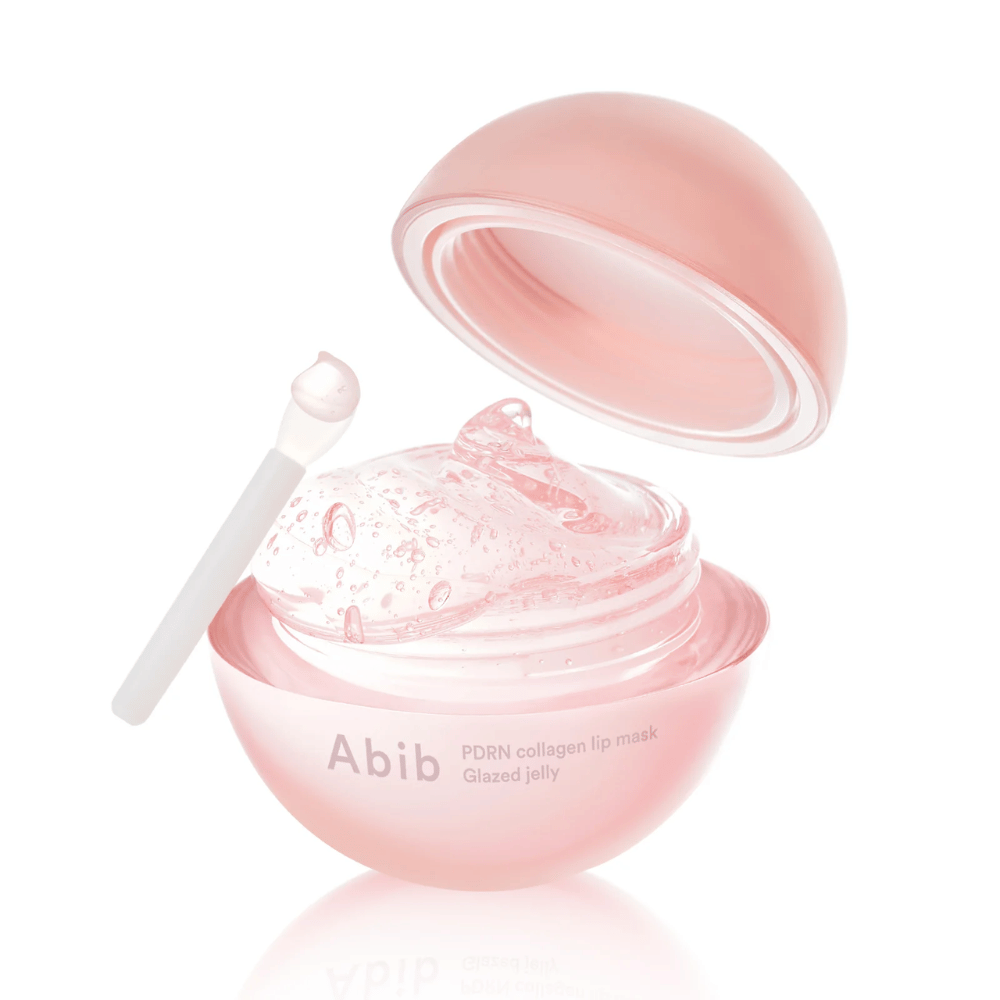Ružová okrúhla nádoba s Abib PDRN Collagen Lip Mask Glazed Jelly, otvorená s vekom nakloneným dozadu. V nádobe je vidieť priehľadný gél s bublinkami spolu s malou špachtľou.