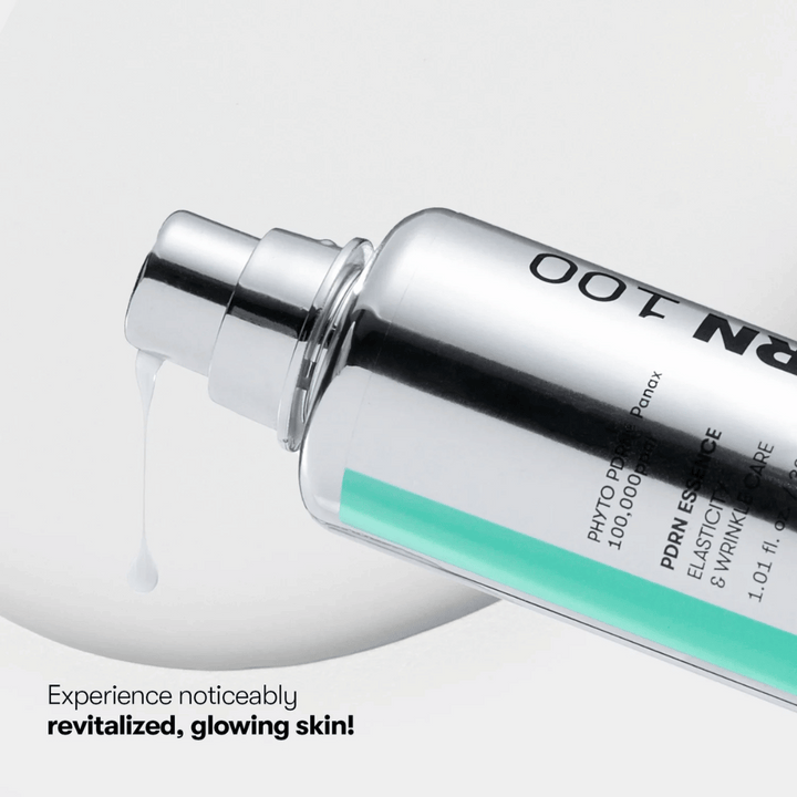 Detailný záber na striebornú pumpovaciu fľašu s VT PDRN Essence 100. Biely esenciálny prípravok vyteká z trysky a text na obrázku znie: "Zažite viditeľne revitalizovanú, žiarivú pokožku!"