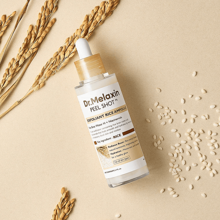 Dr.Melaxin Peel Shot Rice Ampoule ležiaca na pieskovej ploche s ryžou a klasom, exfoliačná tvárová ampulka, ktorá kombinuje jemný peeling s intenzívnou hydratáciou.
