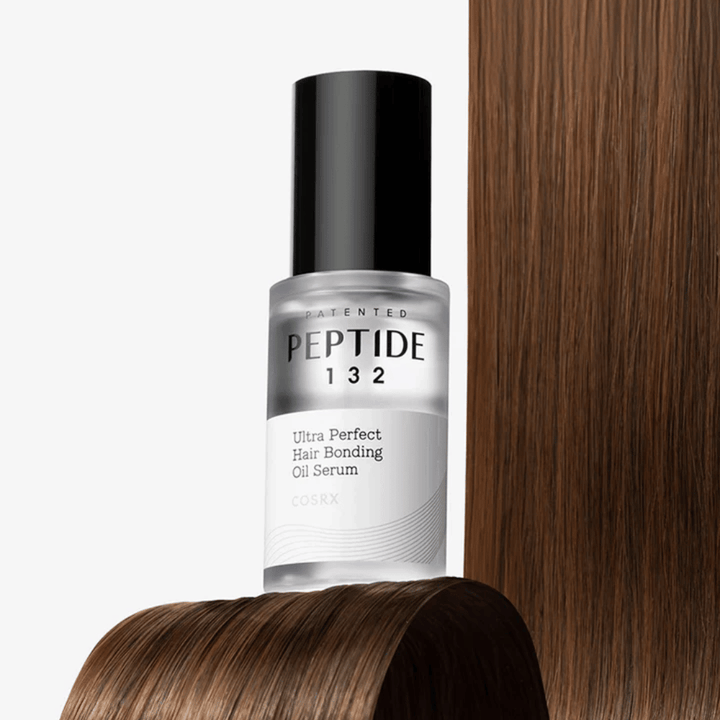 COSRX Peptide 132 Ultra Perfect Hair Bonding Oil Serum umiestnený proti lesklým vlasom – poskytuje silu, jemnosť a lesk.