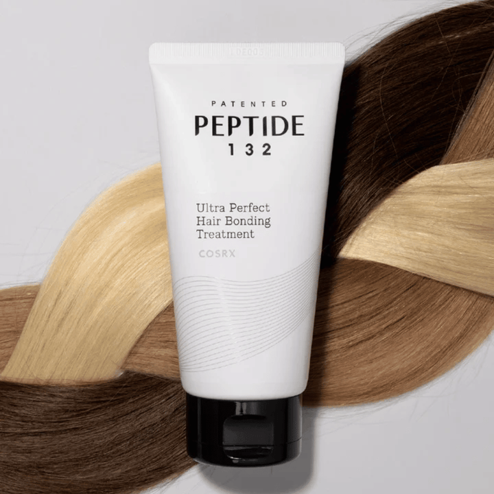 COSRX Peptide 132 Ultra Perfect Hair Bonding Treatment umiestnený proti zapleteným vlasom v rôznych odtieňoch – symbolizuje opravný a posilňujúci účinok.