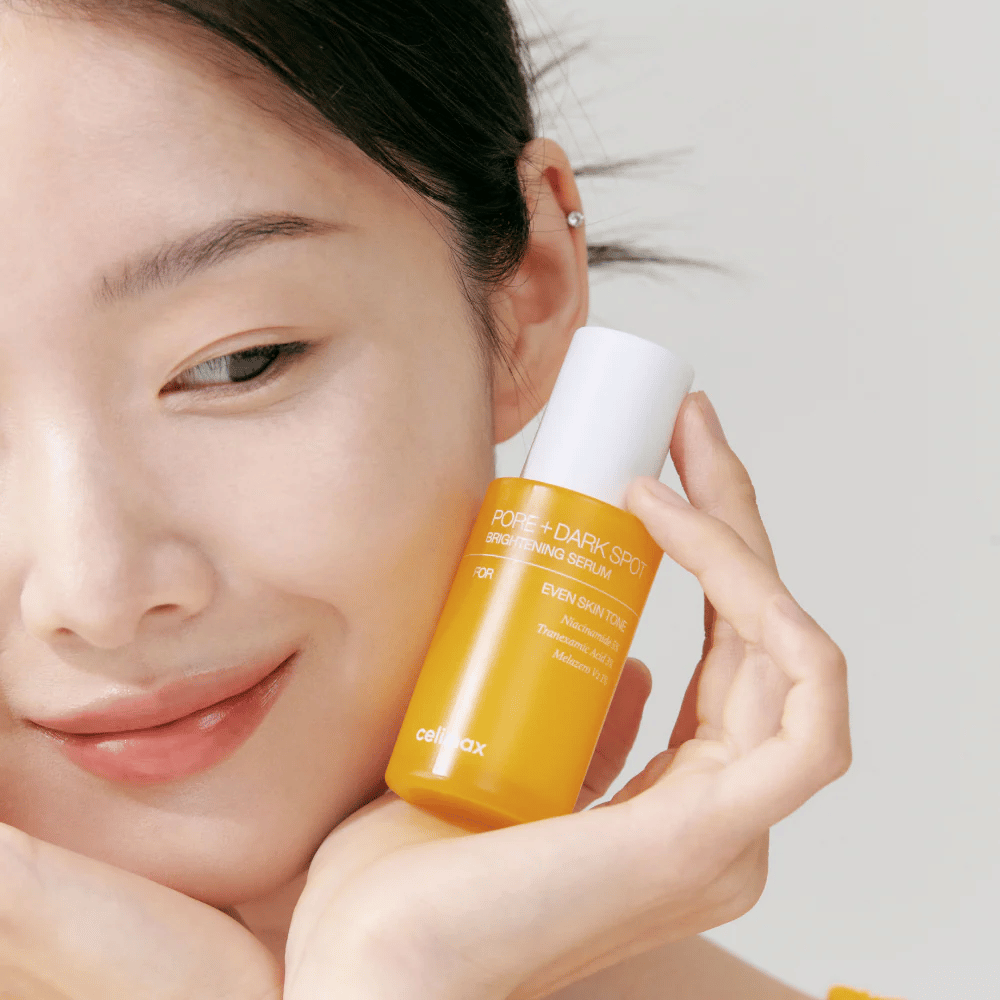 Model drží Celimax Pore + Dark Spot Brightening Serum blízko tváre, ukazuje žiarivú pleť.