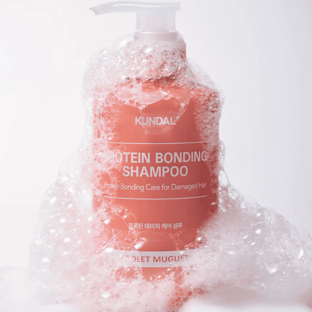 KUNDAL Protein Bonding Shampoo Violet Muguet pokrytý bohatou penou, opravný šampón pre poškodené vlasy.