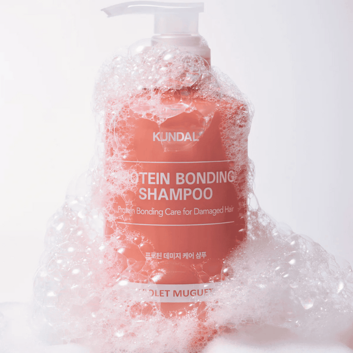 KUNDAL Protein Bonding Shampoo Violet Muguet pokrytý bohatou penou, opravný šampón pre poškodené vlasy.