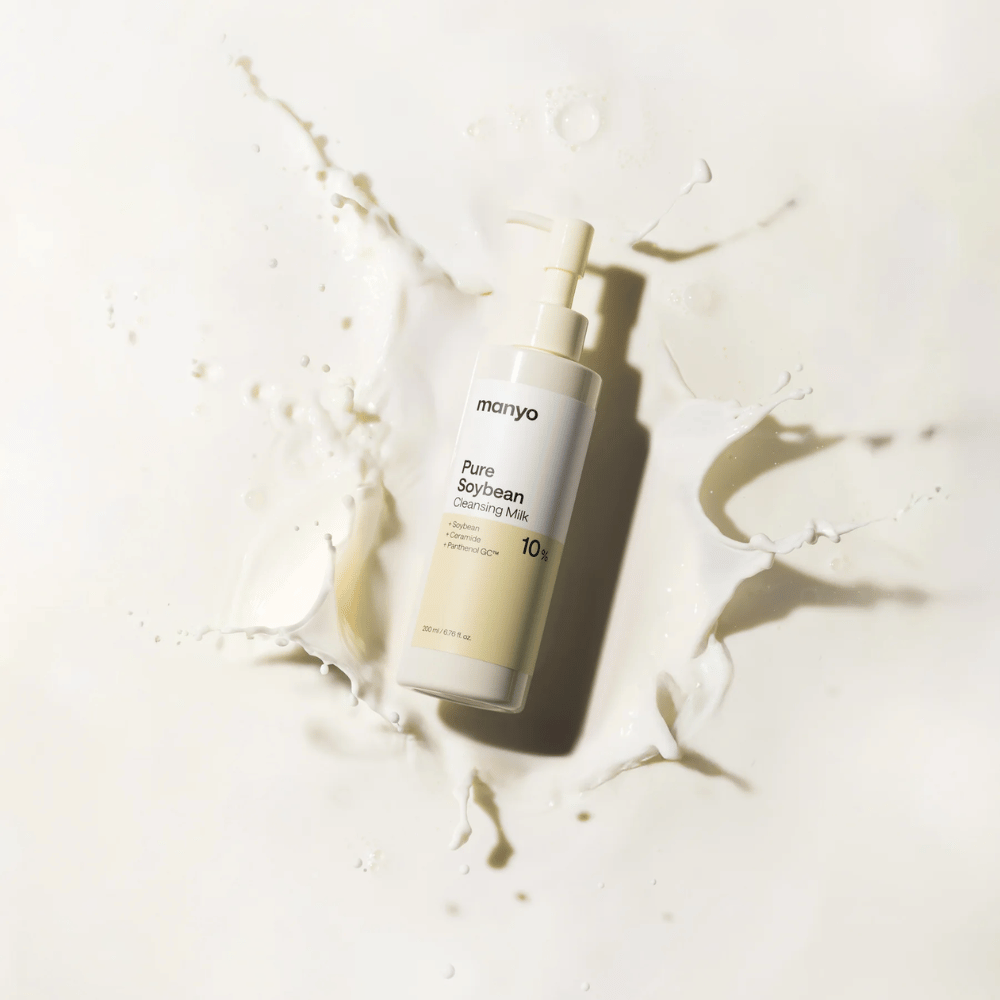 1. Ma:nyo Pure Soybean Cleansing Milk – jemné čistiace mlieko so sójou vo fľaši s pumpičkou obklopenej kvapkami mlieka na svetlom pozadí