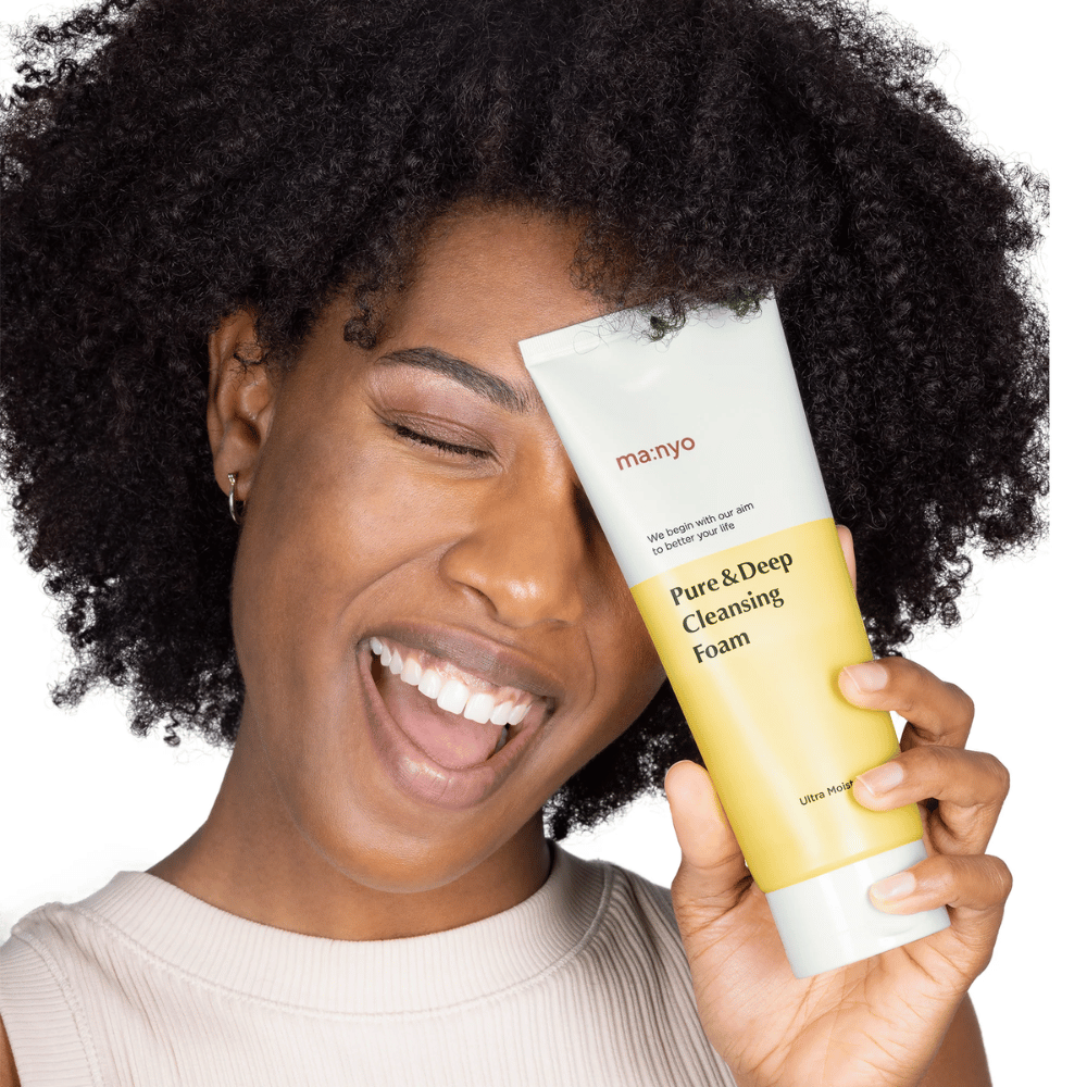 Žena s kučeravými vlasmi drží Ma:nyo Pure & Deep Cleansing Foam – jemné kórejské čistenie, ktoré efektívne odstraňuje nečistoty a make-up bez vysúšania pokožky.