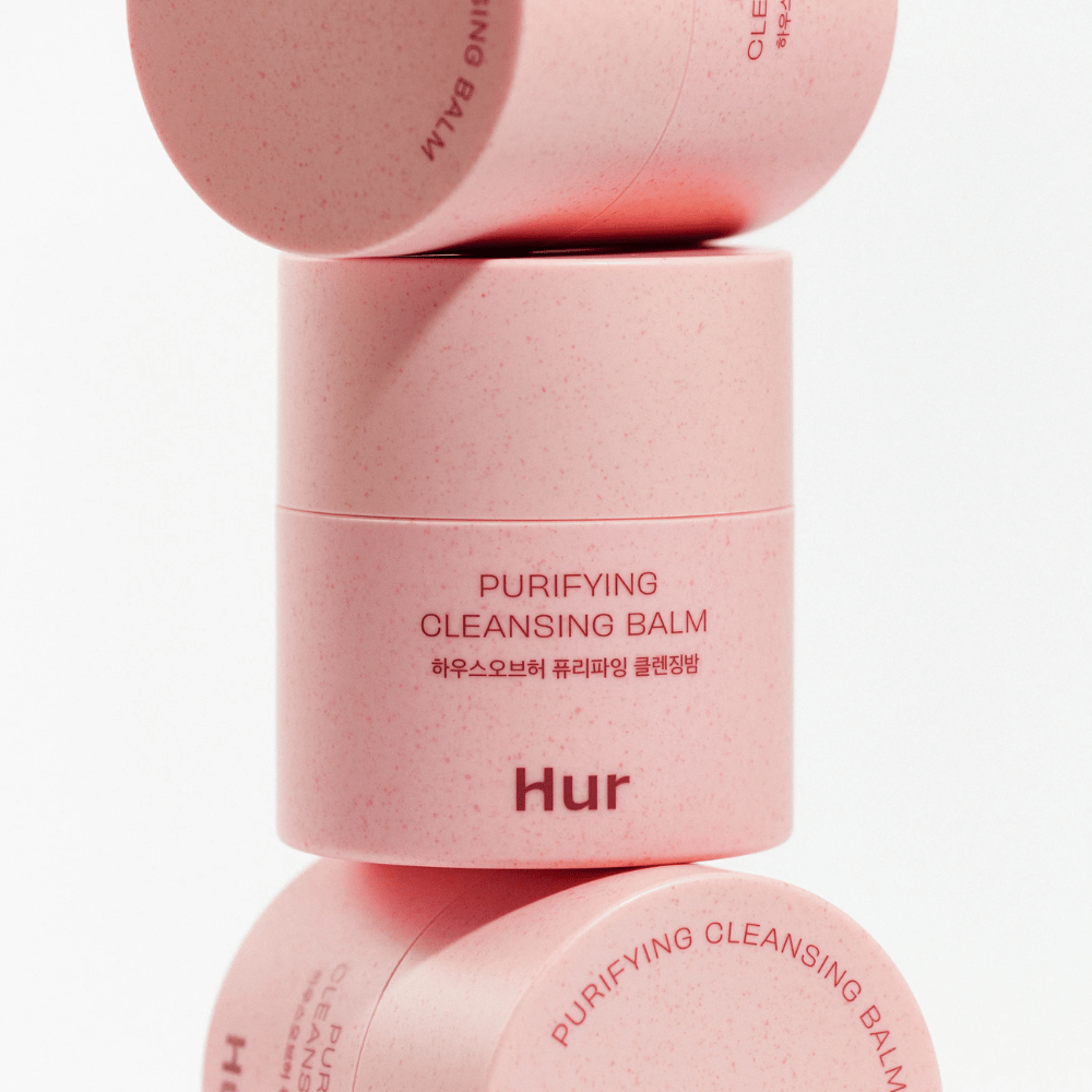 Ako Purifying Cleansing Balm v ružovom balení naskladané v štúdiu. Čistiaci balzam, ktorý účinne rozpúšťa make-up, maz a nečistoty bez vysušovania pokožky.