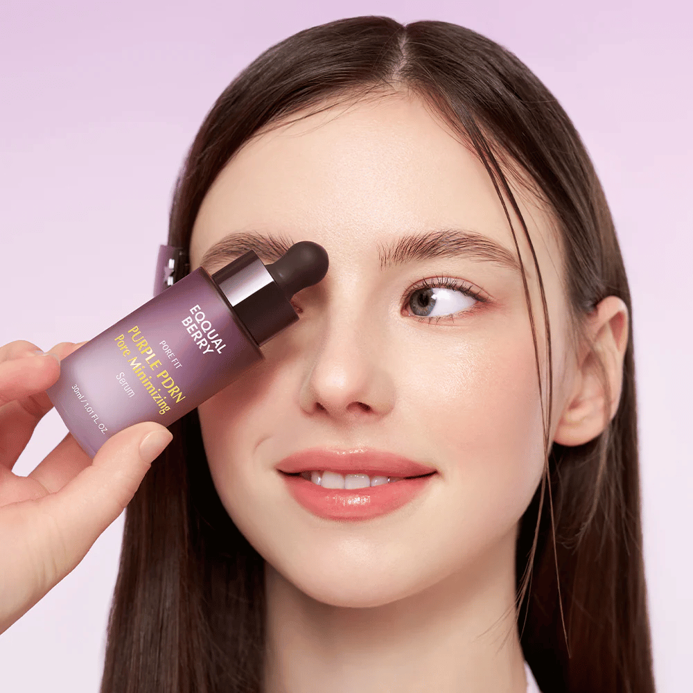Mladá žena s hladkou pleťou drží fľašu Equal Berry Purple PDRN Pore Minimizing Serum pri čele, na svetlofialovom pozadí.
