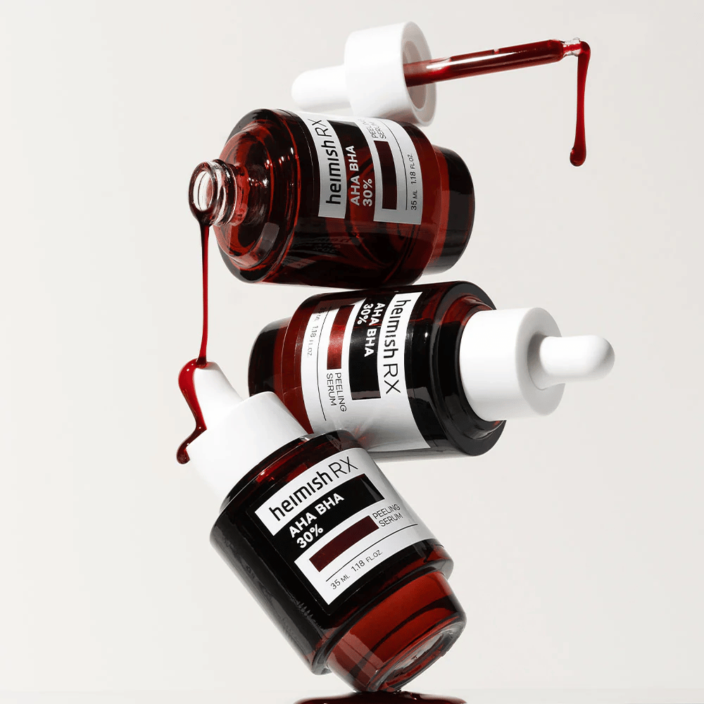 Tri fľaše Heimish RX AHA BHA 30% Peeling Serum v dynamickej kompozícii, s červeným sérom kvapkajúcim z pipiet.