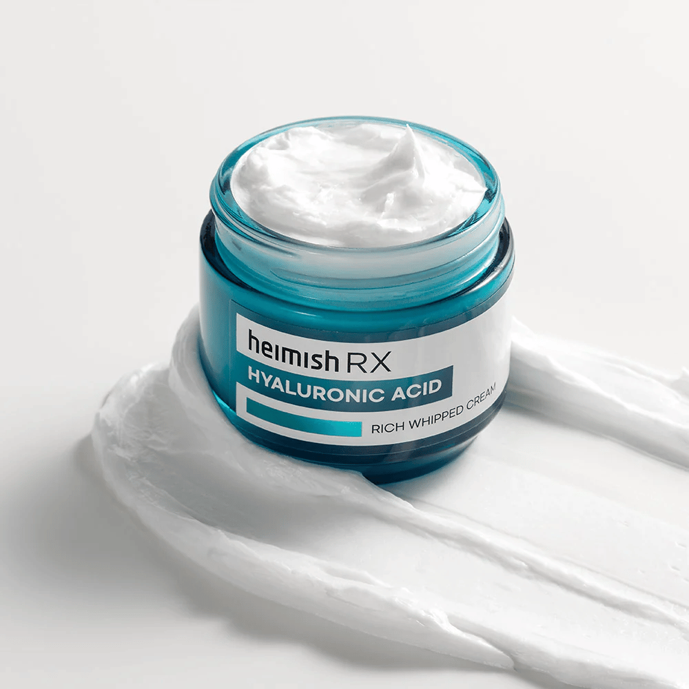 Heimish RX Hyaluronic Acid Rich Whipped Cream v modrej sklenenej nádobe s bohatou a nadýchanou konzistenciou, rozprestretou na bielom pozadí. Intenzívne hydratačný pleťový krém s kyselinou hyalurónovou pre hĺbkovú hydratáciu a jemnú pokožku.