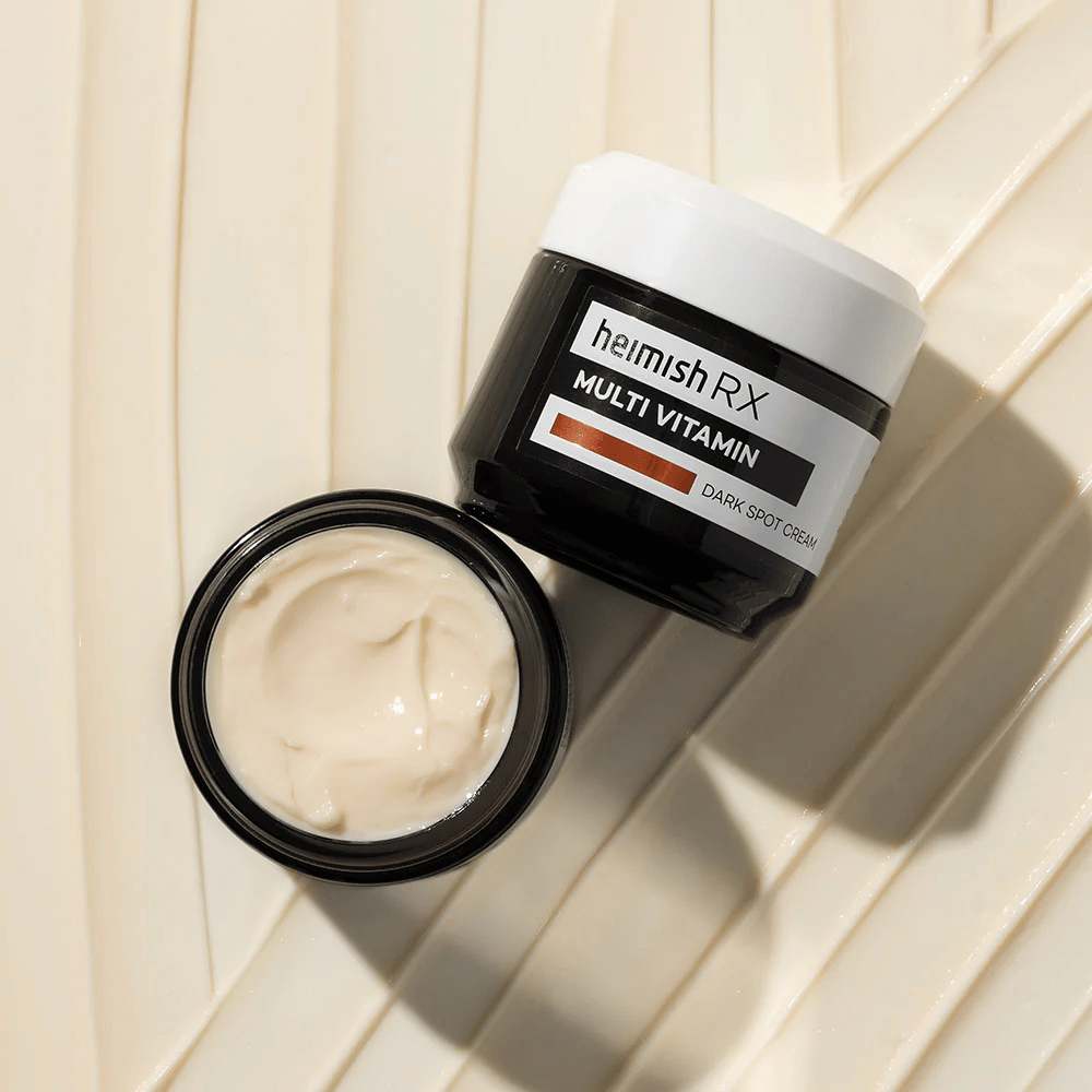 heimish RX Multi Vitamin Dark Spot Cream – výživný pleťový krém na redukciu tmavých škvŕn a vyrovnanie tónu pleti. Hladká textúra krému je zobrazená v otvorenej nádobe s elegantným balením.