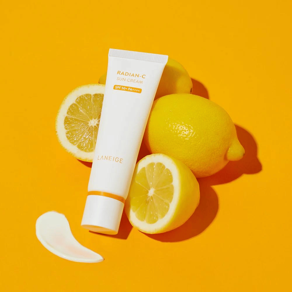 LANEIGE Radian-C Sun Cream SPF 50+ PA++++ s citrónmi a kvapkou opaľovacieho krému na farebnom žltom pozadí.