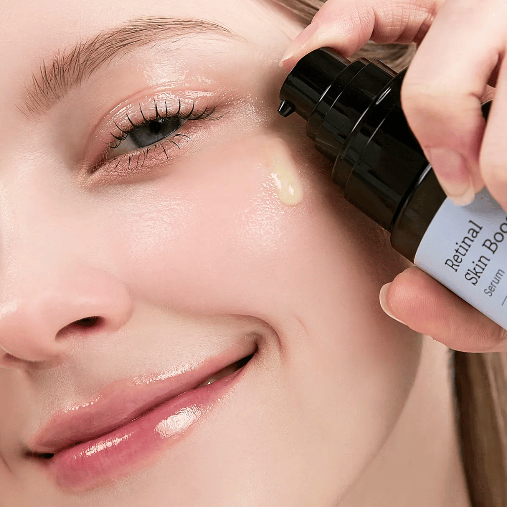 Osoba aplikuje Meditherapy Retinal Skin Booster Serum blízko oka. Sérum má ľahký, žltý tón a dodáva pleti jas a pevnosť.