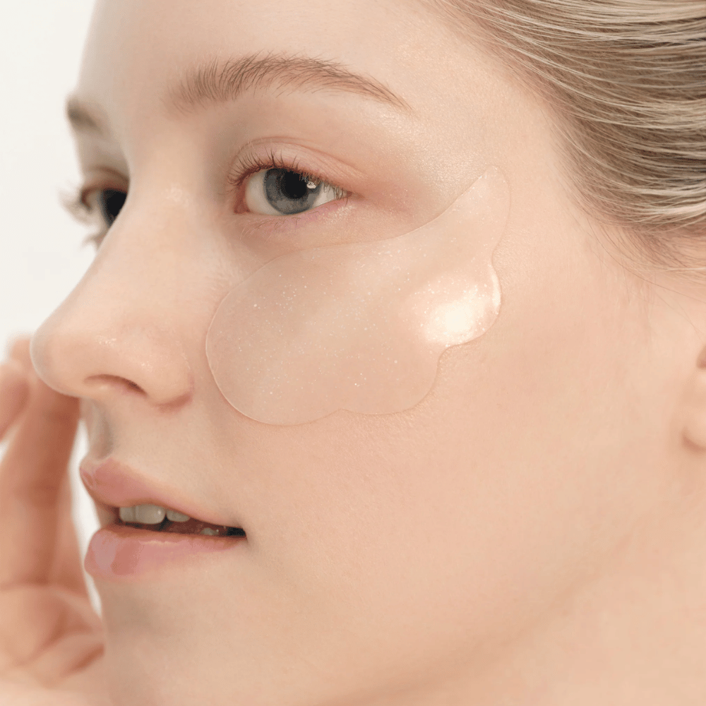 Detailný záber na modelku, ktorá aplikuje Beauty of Joseon under eye patch pod oko pre hydratáciu, lesk a spevňujúci efekt.
