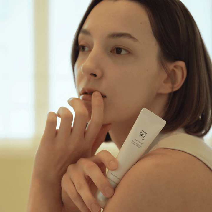 Model drží Beauty of Joseon Revive Eye Serum a opatrne aplikuje na pokožku pre hydratovaný a hladký obrys očí.