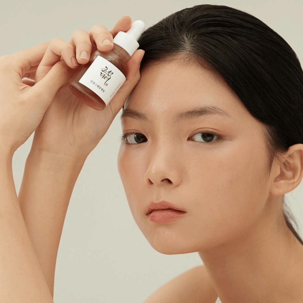 Model drží Beauty of Joseon Revive Serum pri líci – výživné sérum s ženšenom a snail mucin.